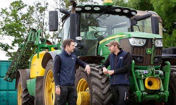 Two farmers stood in front of a tractor